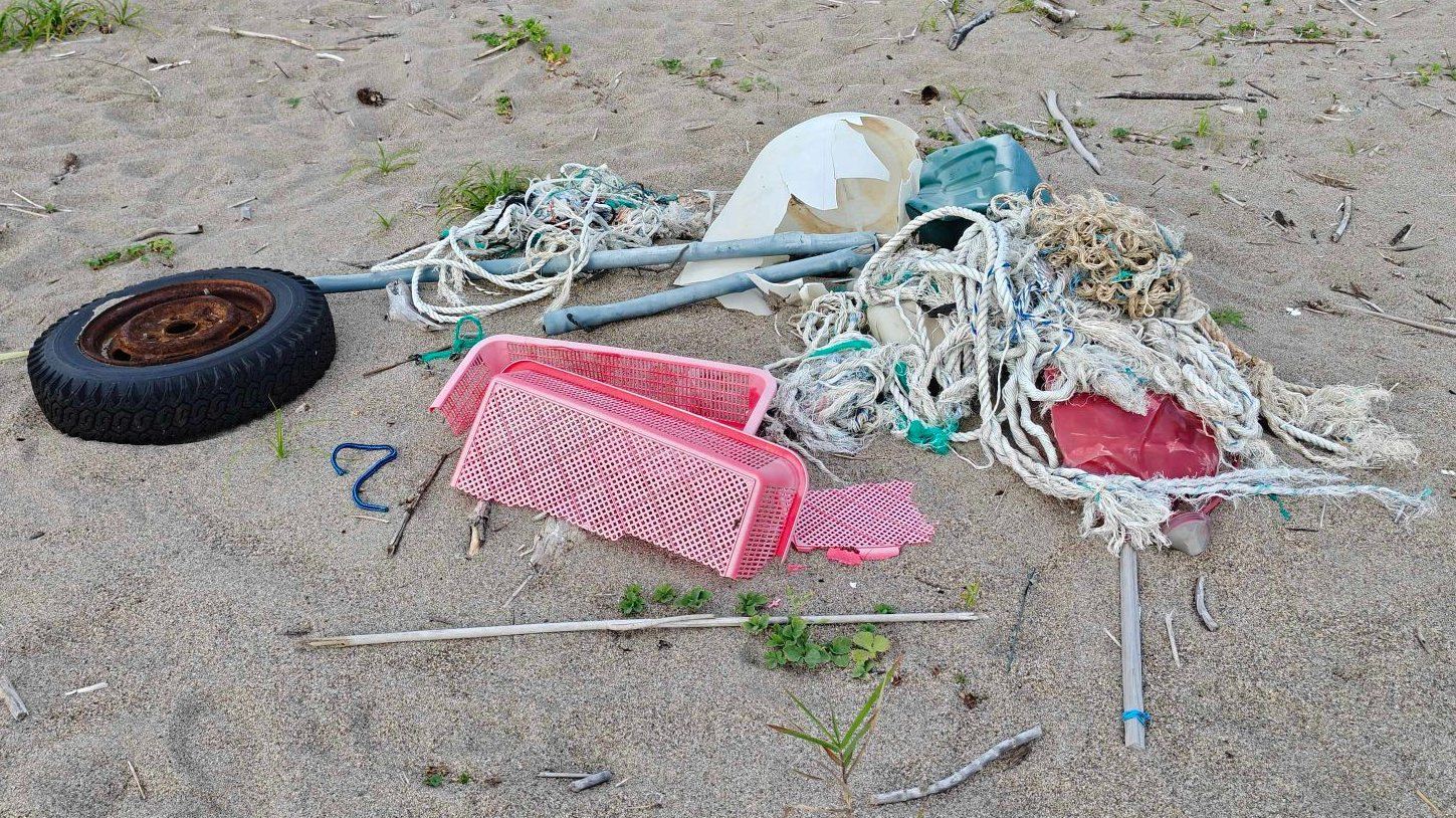 砂浜に漂着したロープ、漁網、かご、タイヤ